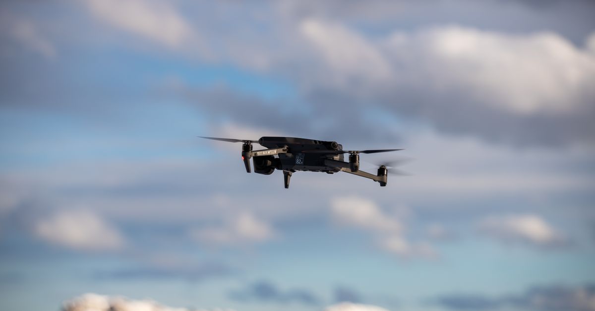 Aerial view of a drone flying over snow-covered mountains with dramatic clouds.